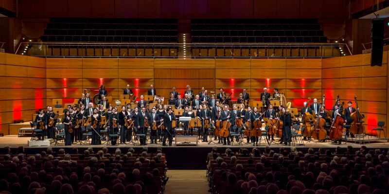 Orchester mit Publikum im ausverkauftem Konzertsaal